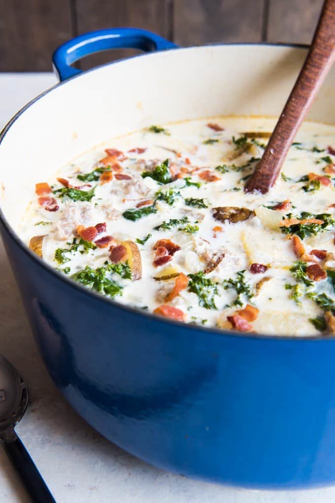 Zuppa Toscana in a large blue pot with a wooden spoon