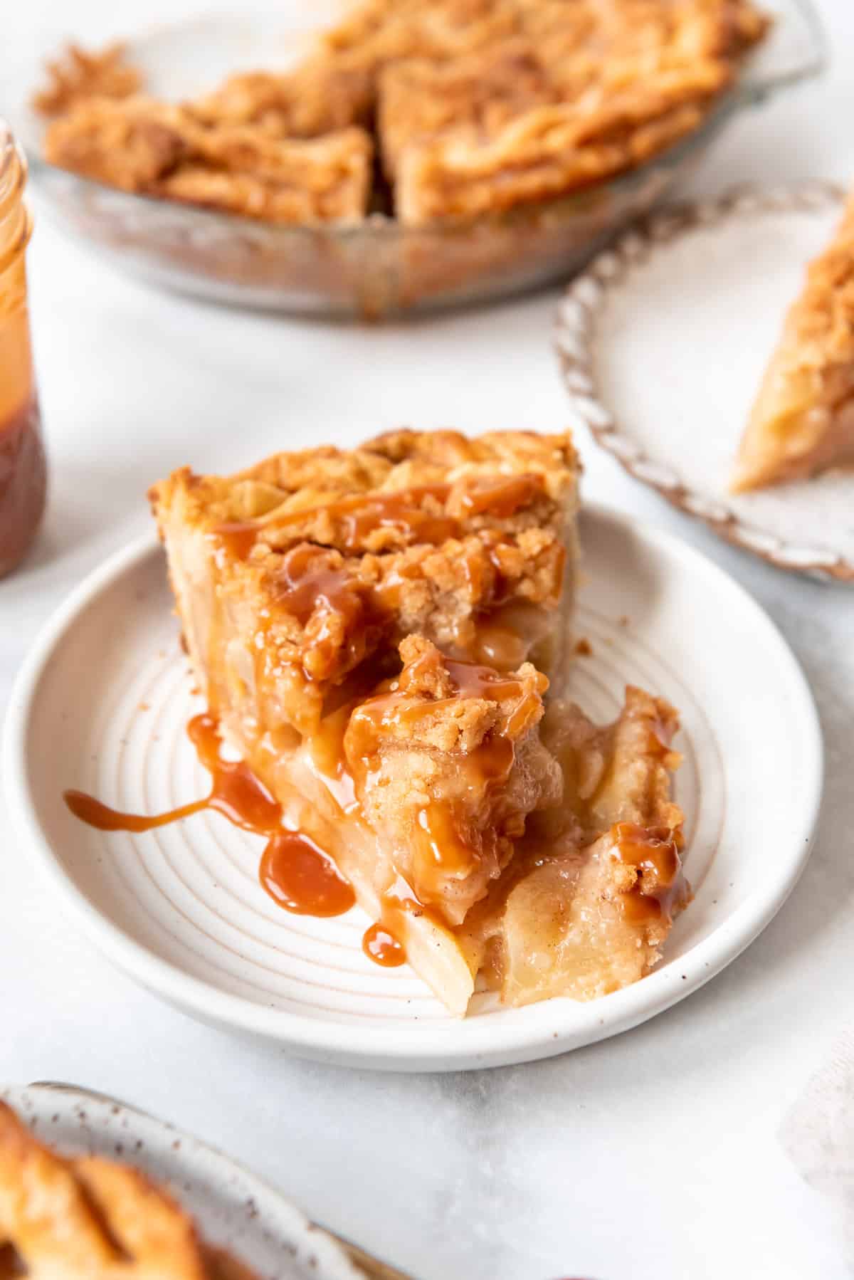 A piece of Dutch pear pie on a plate topped with caramel sauce.