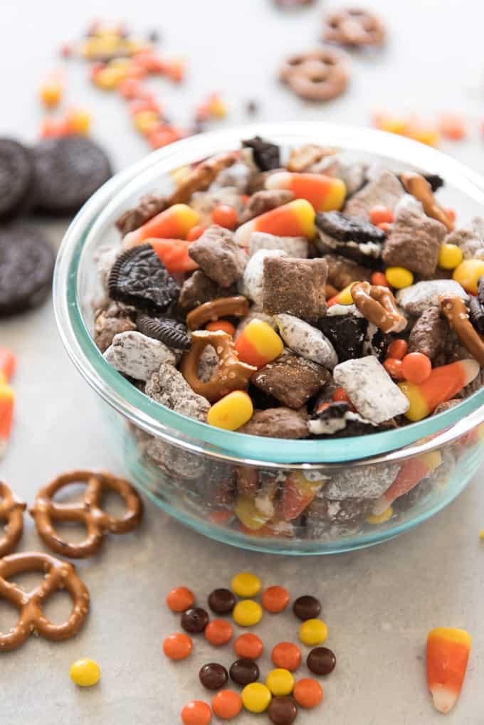 halloween chex mix in a bowl with ingredients scattered around