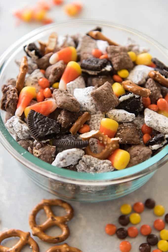 A glass bowl filled with Halloween Chex Mix Muddy Buddies (aka Puppy Chow)