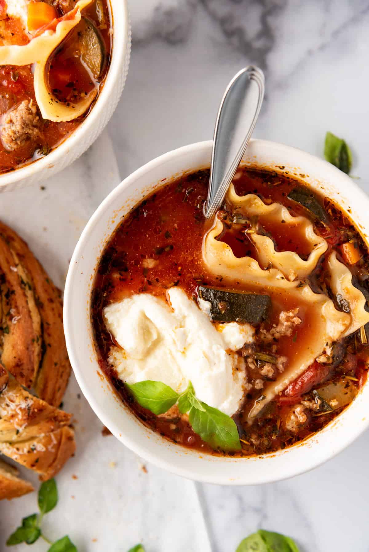 A close up image of a bowl of lasagna soup with a dollop of ricotta cheese in it.