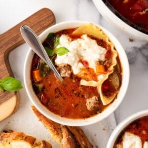 An overhead image of a bowl of lasagna soup next to garlic bread.