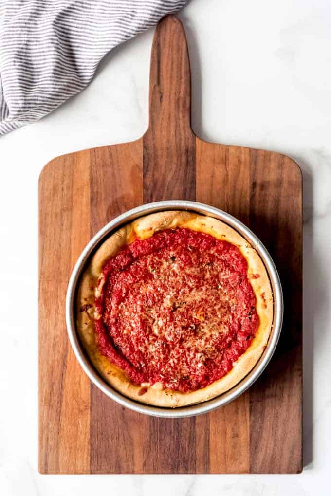 An image of a baked Chicago deep dish cheese pizza on a wooden cutting board.