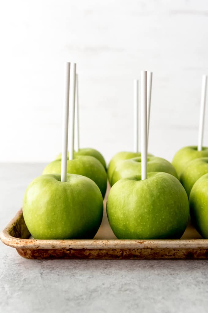 An image of granny smith apples with sticks in them.