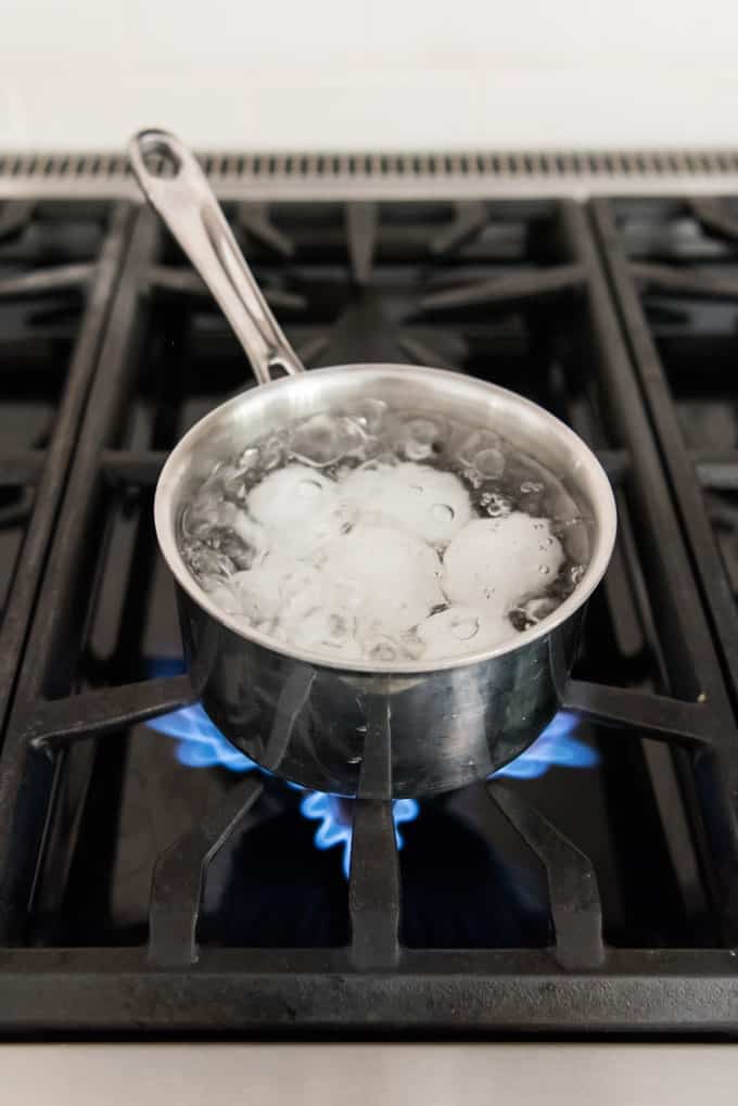 eggs boiling in a pot of water on a stovetop
