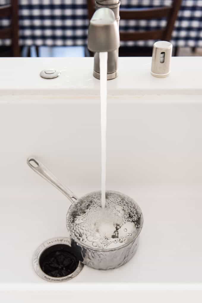 sink faucet pouring water into a pot of eggs