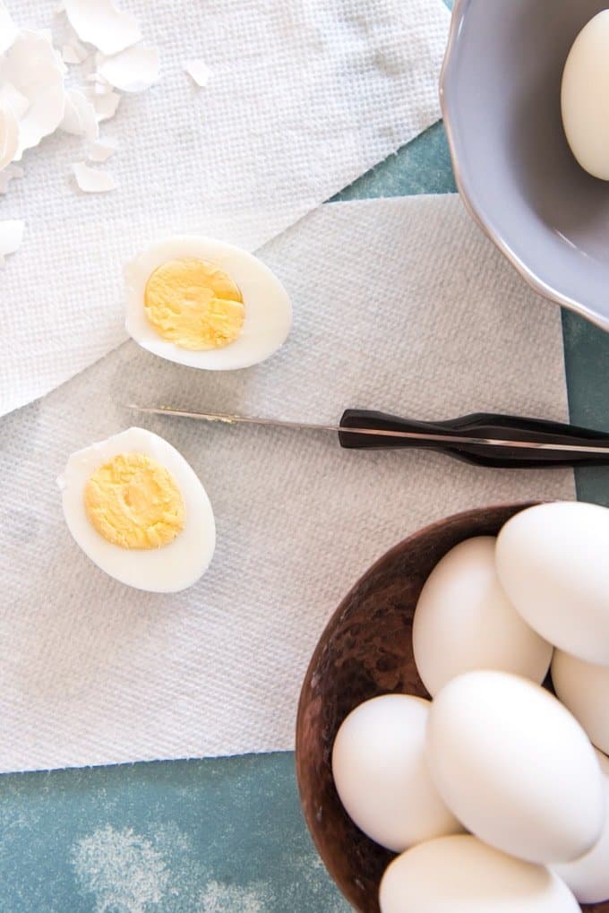 a sliced in half boiled egg on a paper towel with a bowl of eggs down below