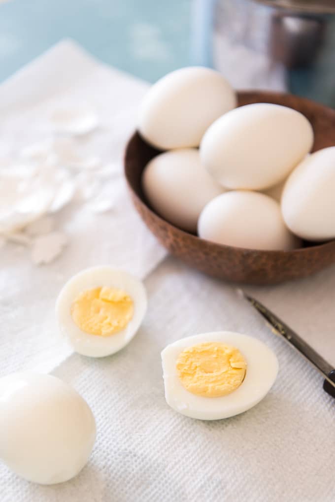 a bowl of eggs behind a sliced hard boiled egg on a paper towel
