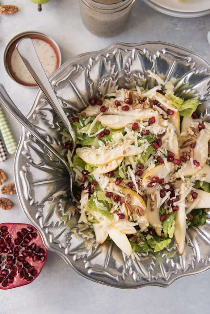 a silver bowl filled with a fancy salad and garnished with pomegranate seeds
