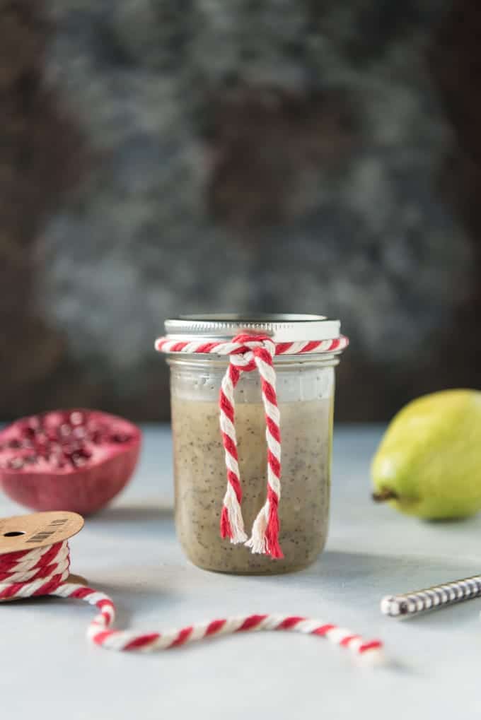 pomegranate and pear in the background with a spool of red and white rope to the side and a mason jar in center with some rope tied around the rim