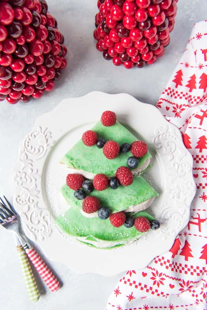 an aerial view of Christmas Tree Crepes with Gingerbread Spice Whipped Cream on a white plate