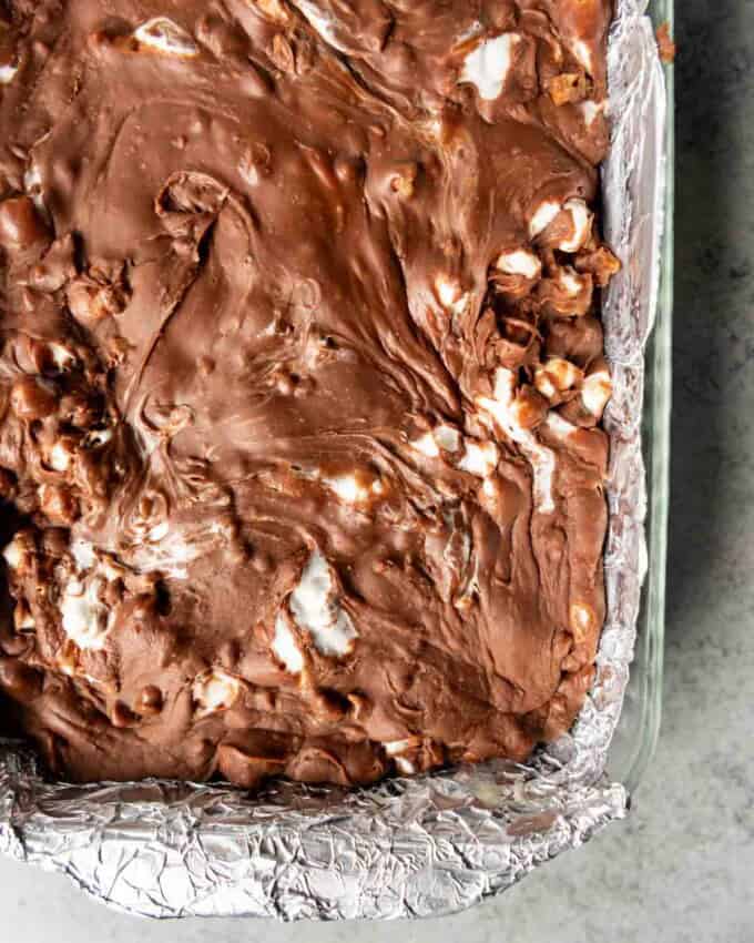 A corner of the rocky road fudge in a foil lined baking dish.