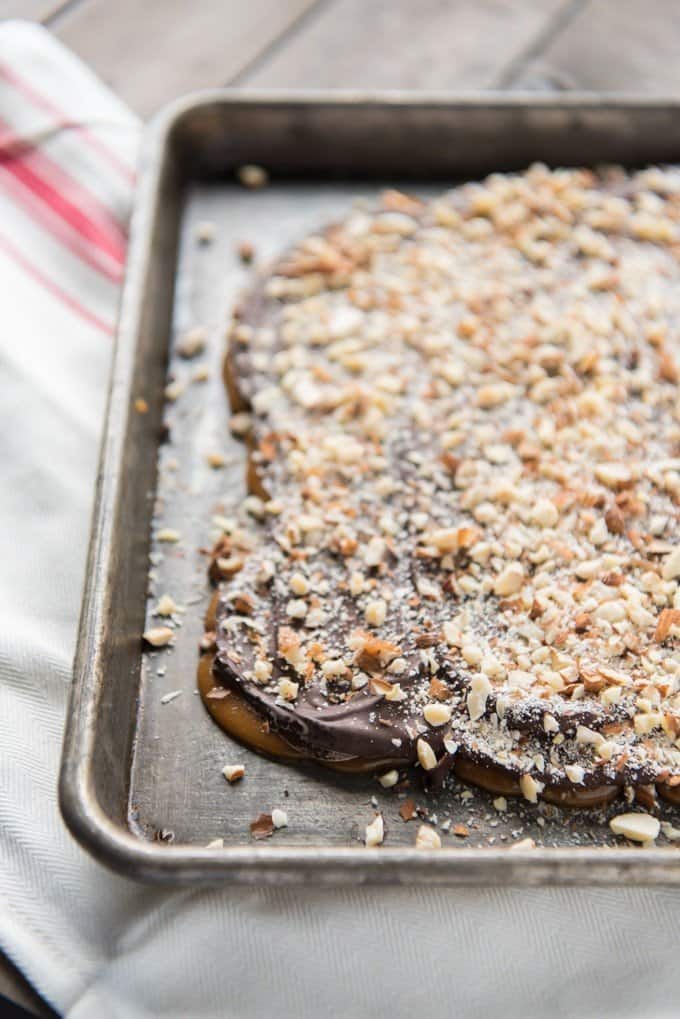 toffee on a baking sheet topped with chocolate and chopped nuts