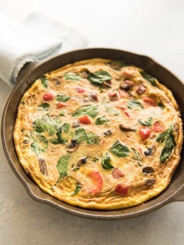 a skillet filled with baked mushroom sausage spinach and red pepper breakfast frittata