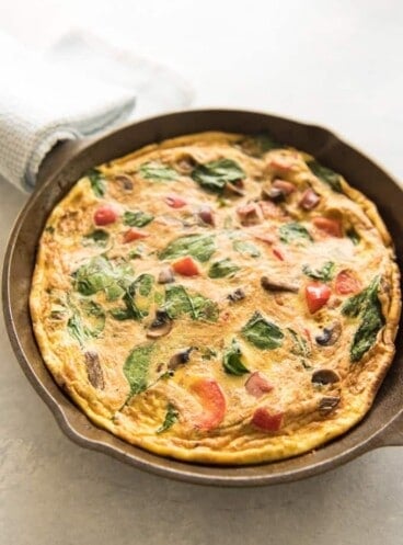 a skillet filled with baked mushroom sausage spinach and red pepper breakfast frittata