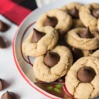 a bowl filled with peanut butteer blossom cookies with a few scattered hershey kisses around it