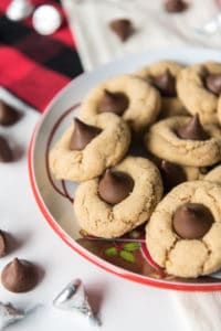 a bowl filled with peanut butteer blossom cookies with a few scattered hershey kisses around it