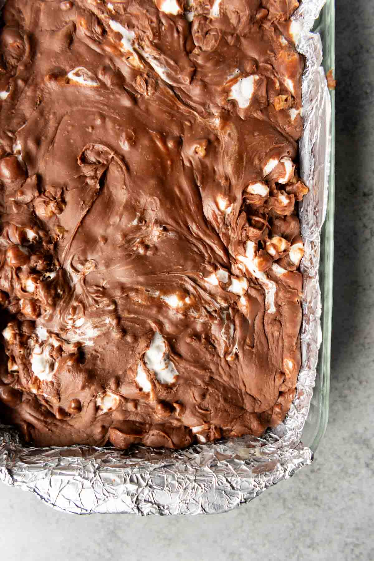 A corner of the rocky road fudge in a foil lined baking dish.