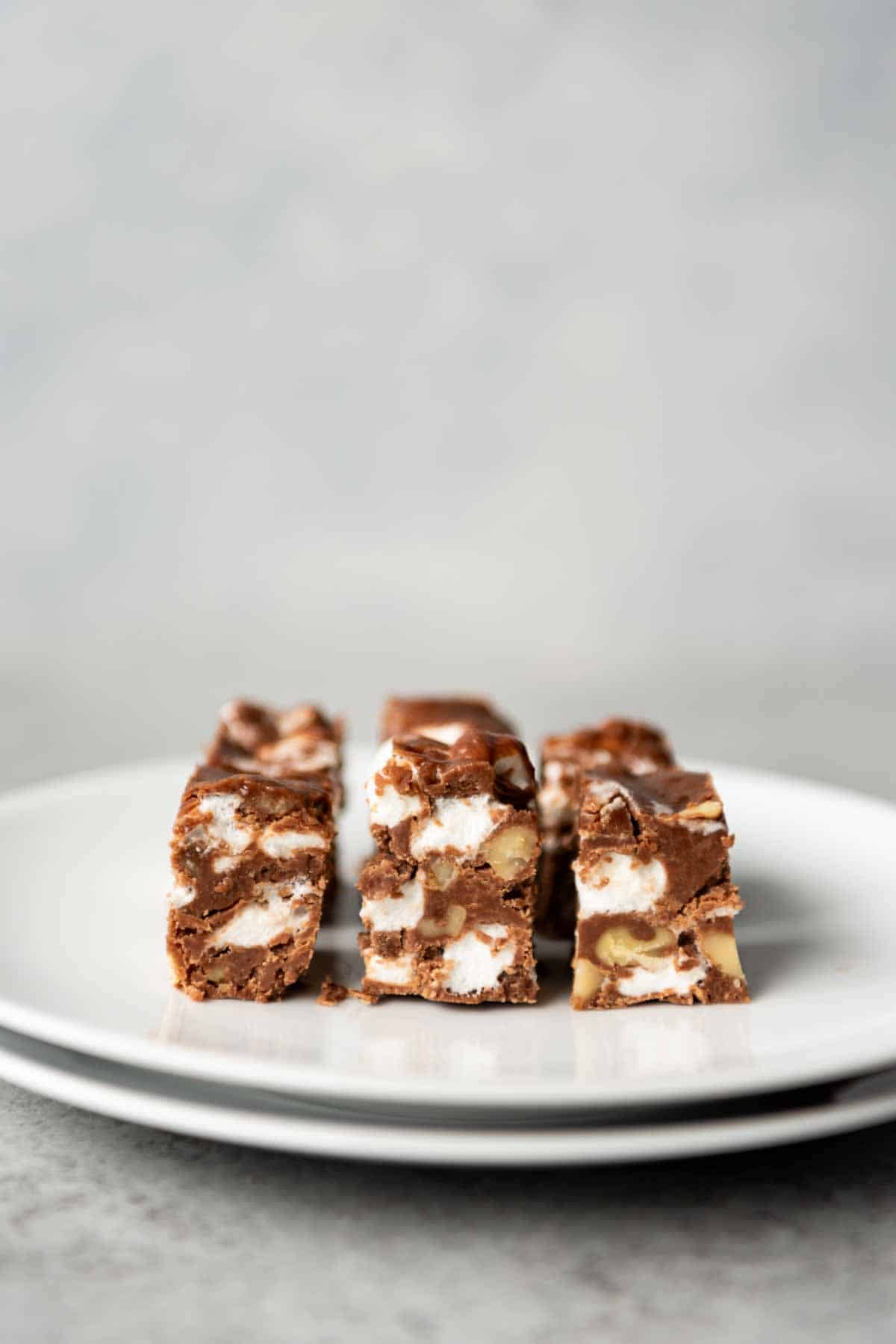 Several pieces of cut fudge on stacked white plates ready to eat.