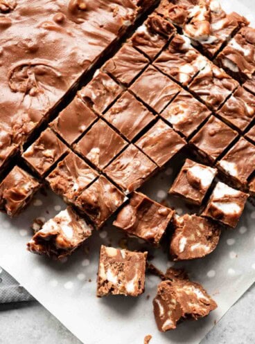 Rocky road fudge chopped into small squares on parchment paper.