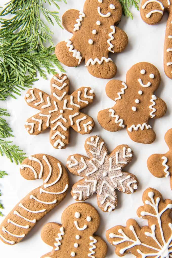 decorated gingerbread cookies next to some green christmas tree sprigs