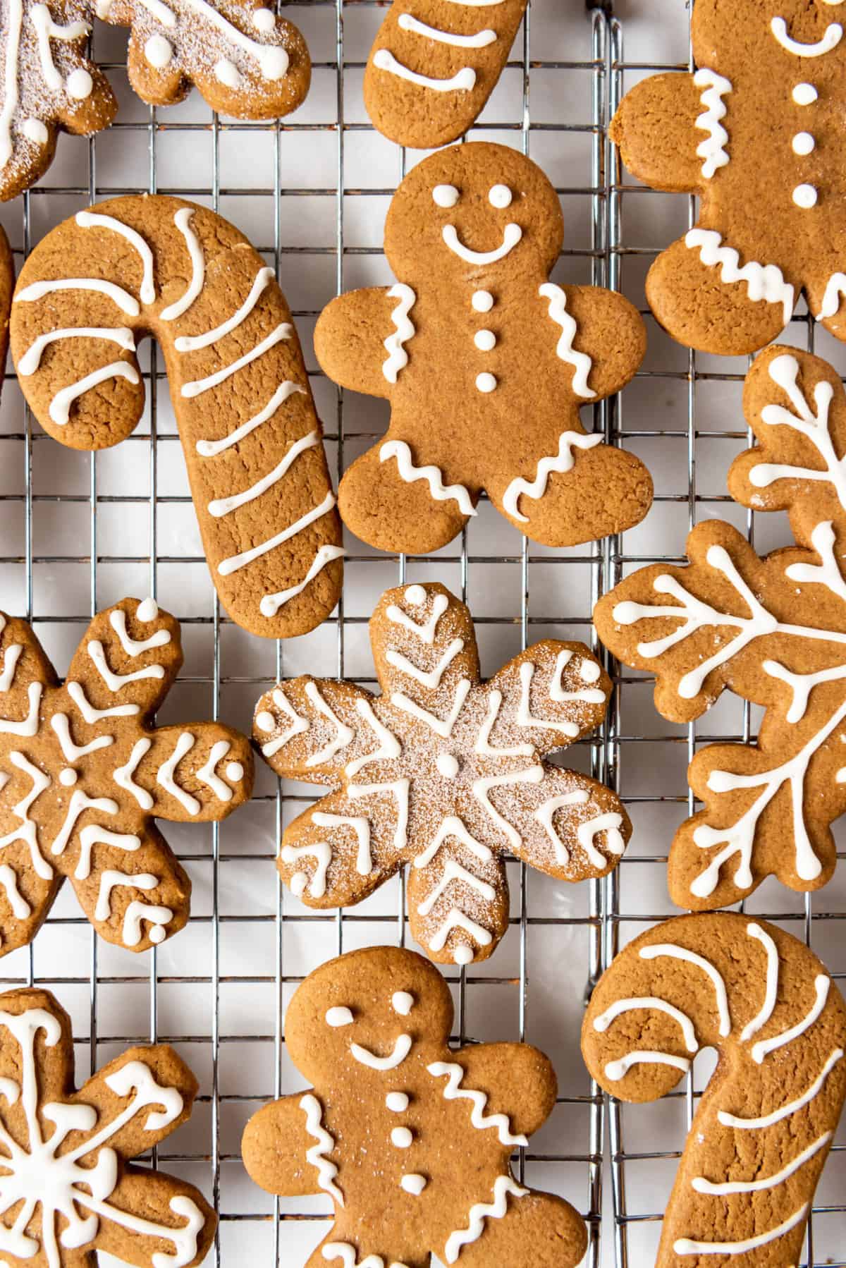 Soft gingerbread cookies cut out like snowflakes, gingerbread men, and candy canes then decorated with easy royal icing.
