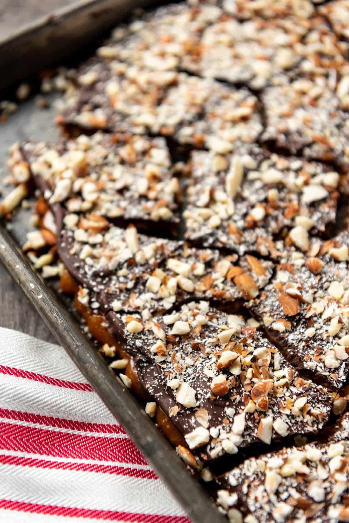 toffee on a baking sheet topped with chocolate and chopped nuts