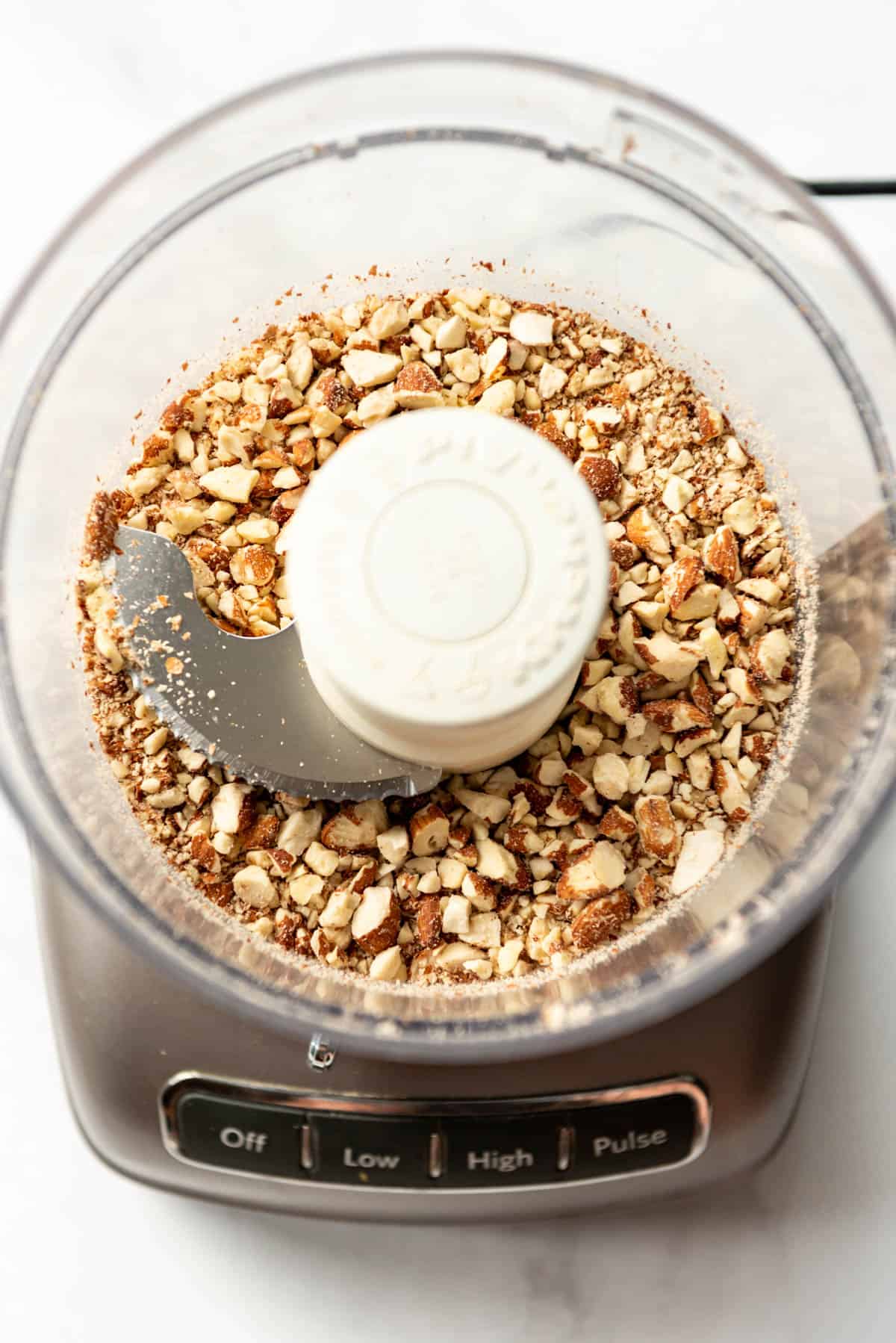 An image of chopped toasted almonds in a food processor.