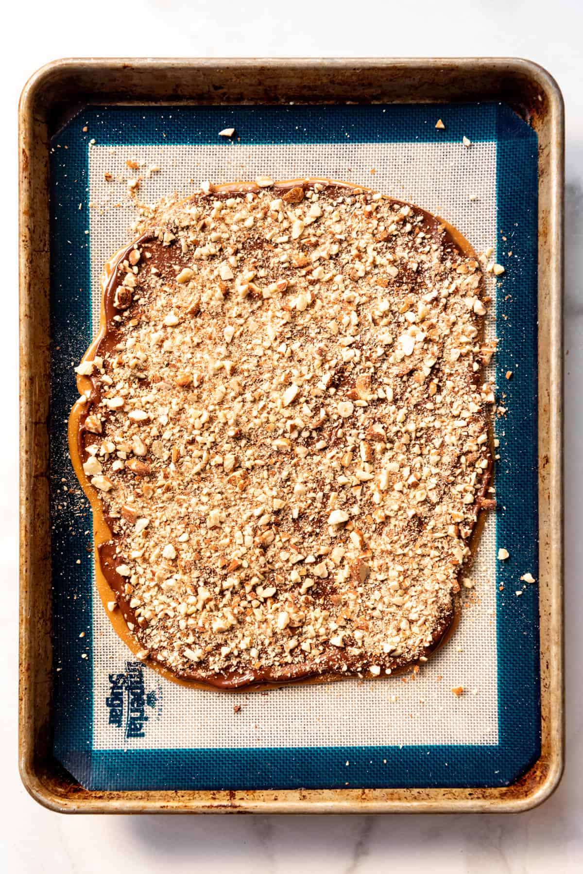 An overhead image of a batch of english toffee with chopped toasted almonds sprinkled on top.