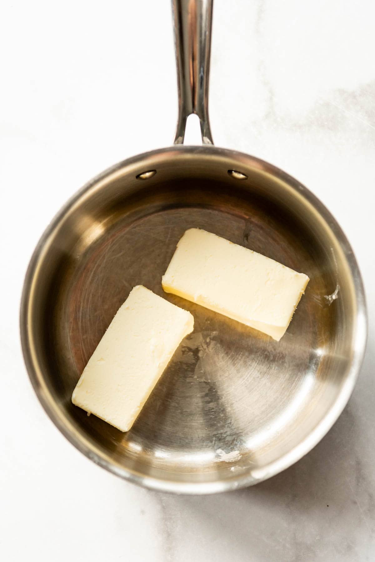 Melting two sticks of butter in a saucepan.