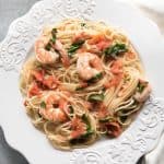 an aerial view of a white plate filled with shrimp and tomato angel hair pasta