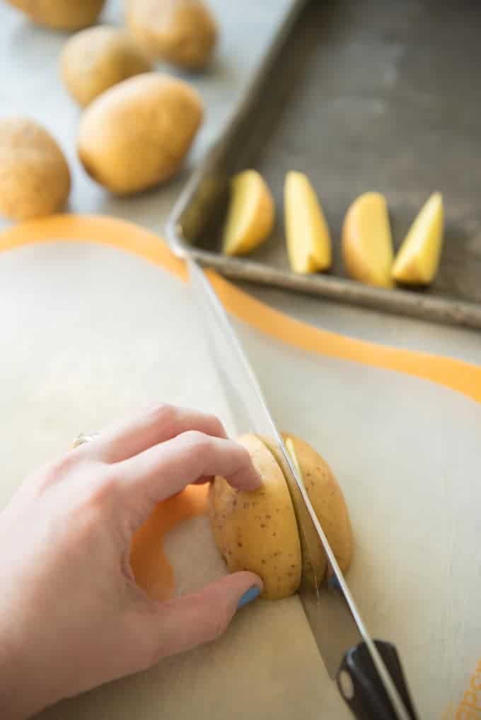 Slicing a golden potato in half with a chef knife