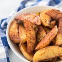 a white bowl filled with bbq roasted potato wedges