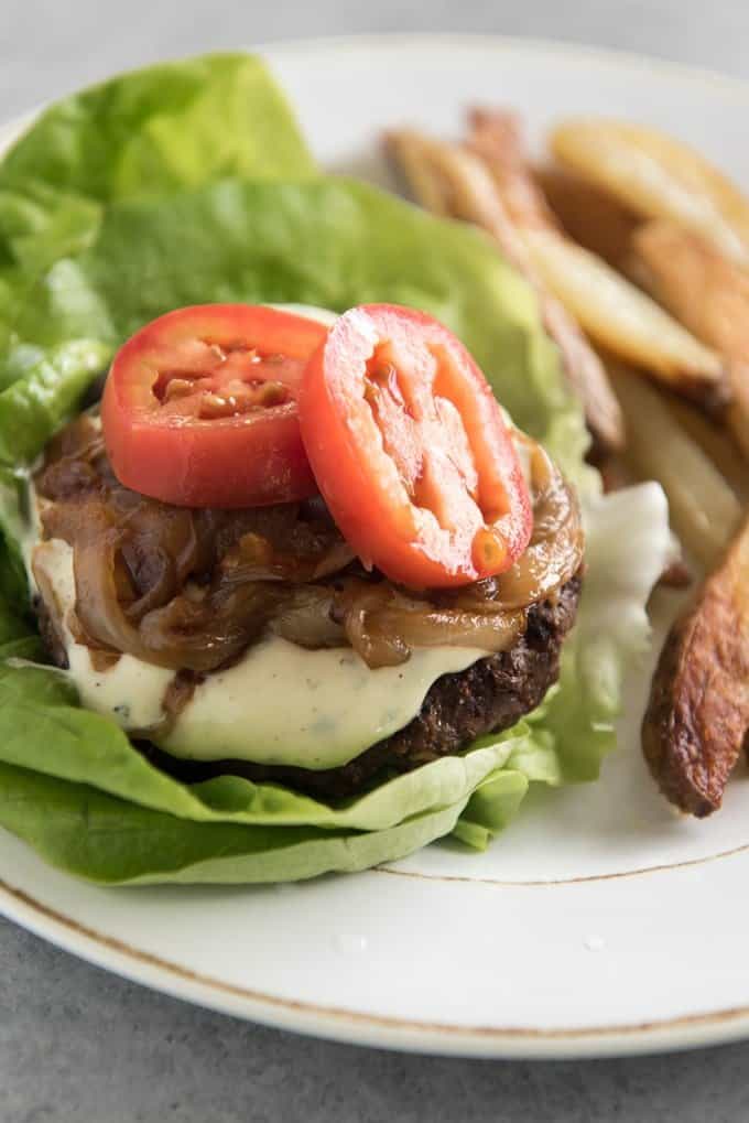 a burger and fries on a plate and the burger is topped with aioli as an example of how you can use it