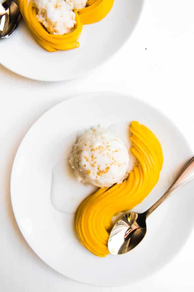 white plates with neatly arranged mango slices and scoops of sticky rice with sauce
