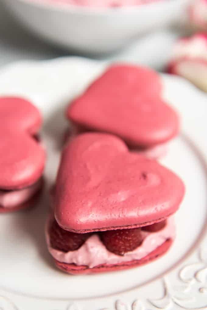 raspberry rose macarons on a white plate