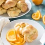 orange rolls on white plates with sliced and whole oranges