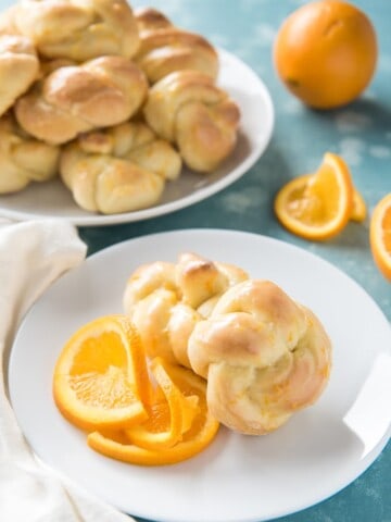 orange rolls on white plates with sliced and whole oranges