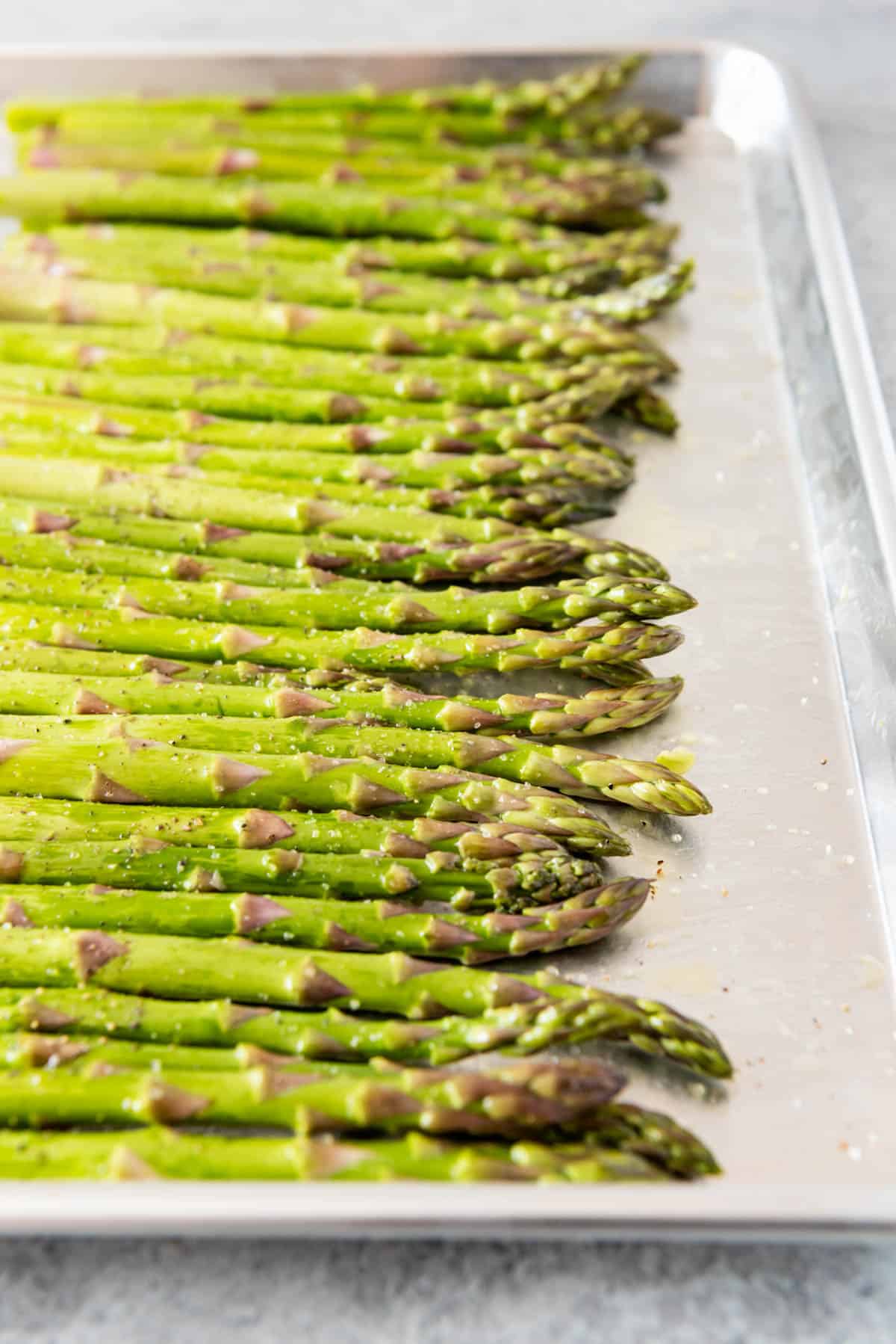 A close angled shot of asparagus on a baking sheet.