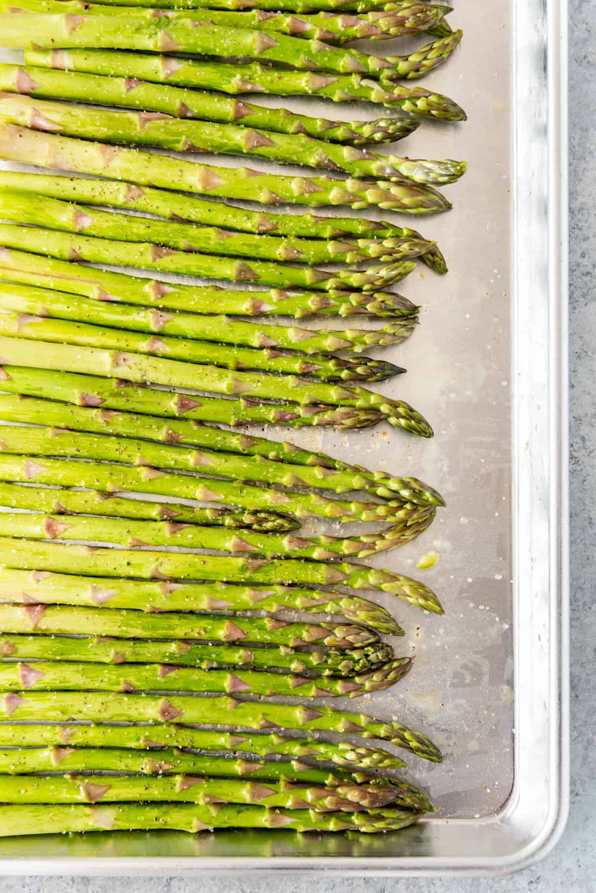 A row of green asparagus on a baking sheet.