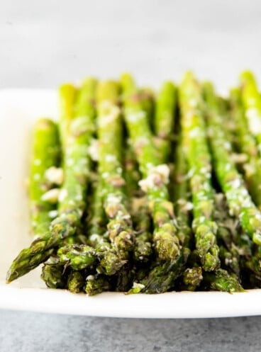 A plate with rows of asparagus topped with cheese.