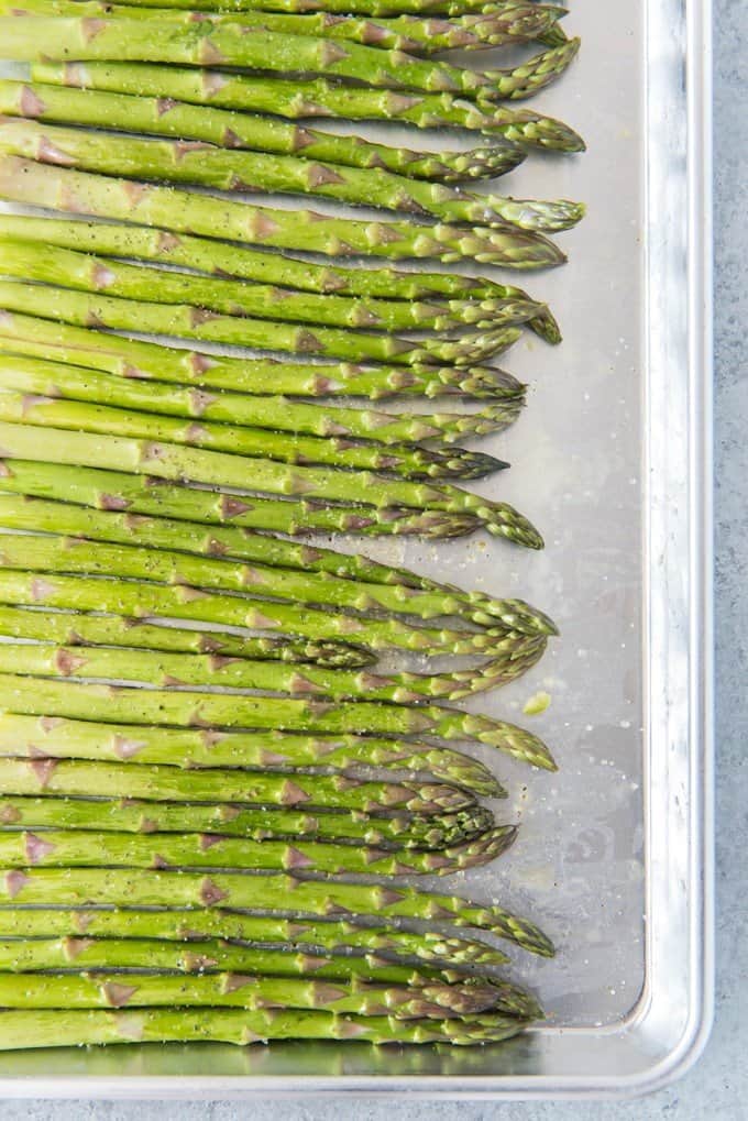 a row of green asparagus on a baking seet