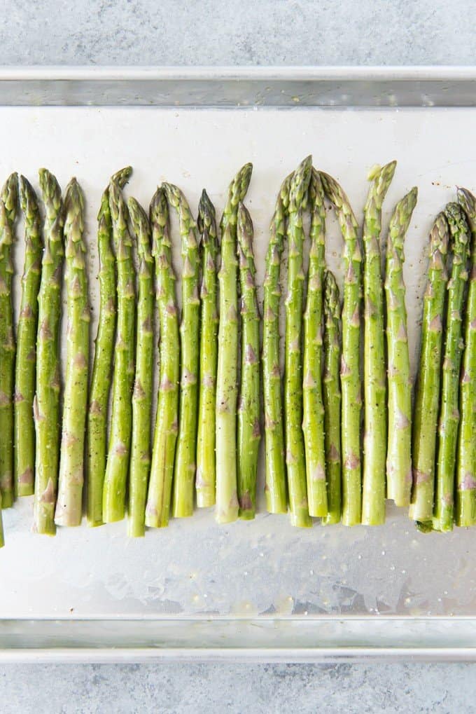 a row of asparagus on a baking sheet