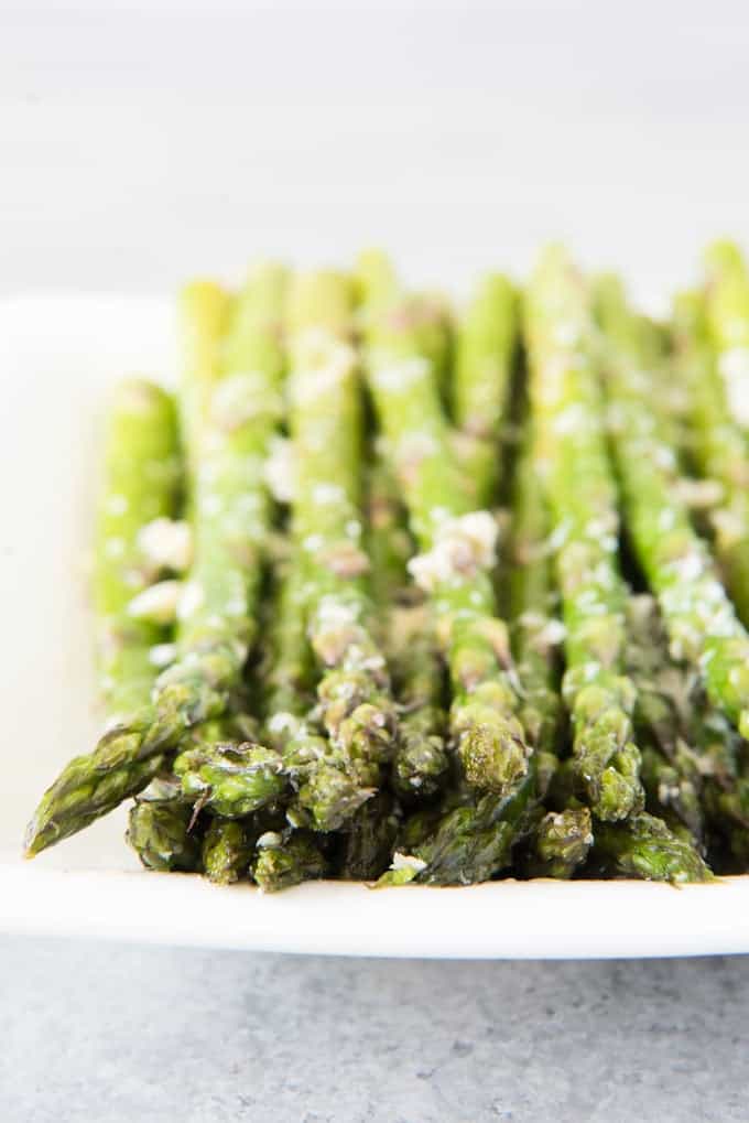 a plate with rows of asparagus topped with cheese