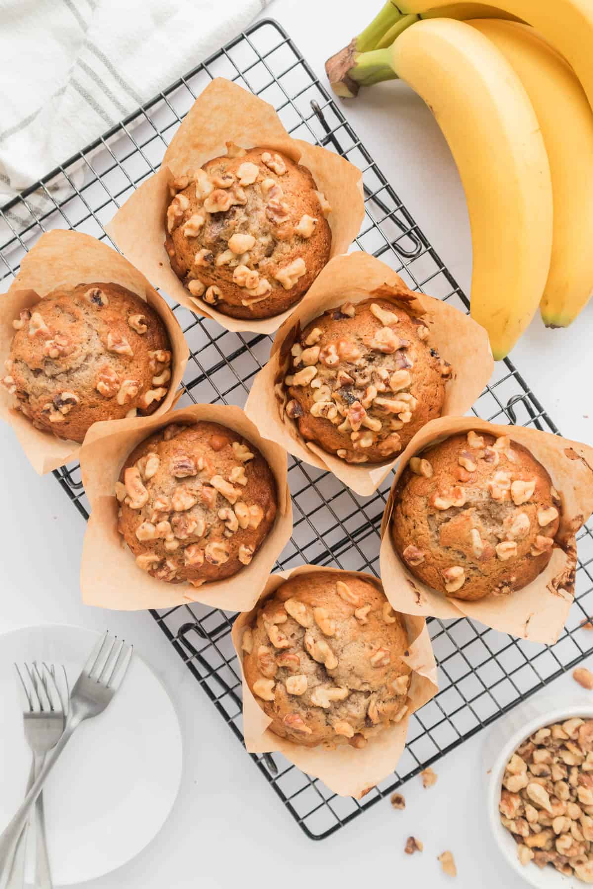 An overhead image of banana nut muffins on a wire cooling rack next to bananas.