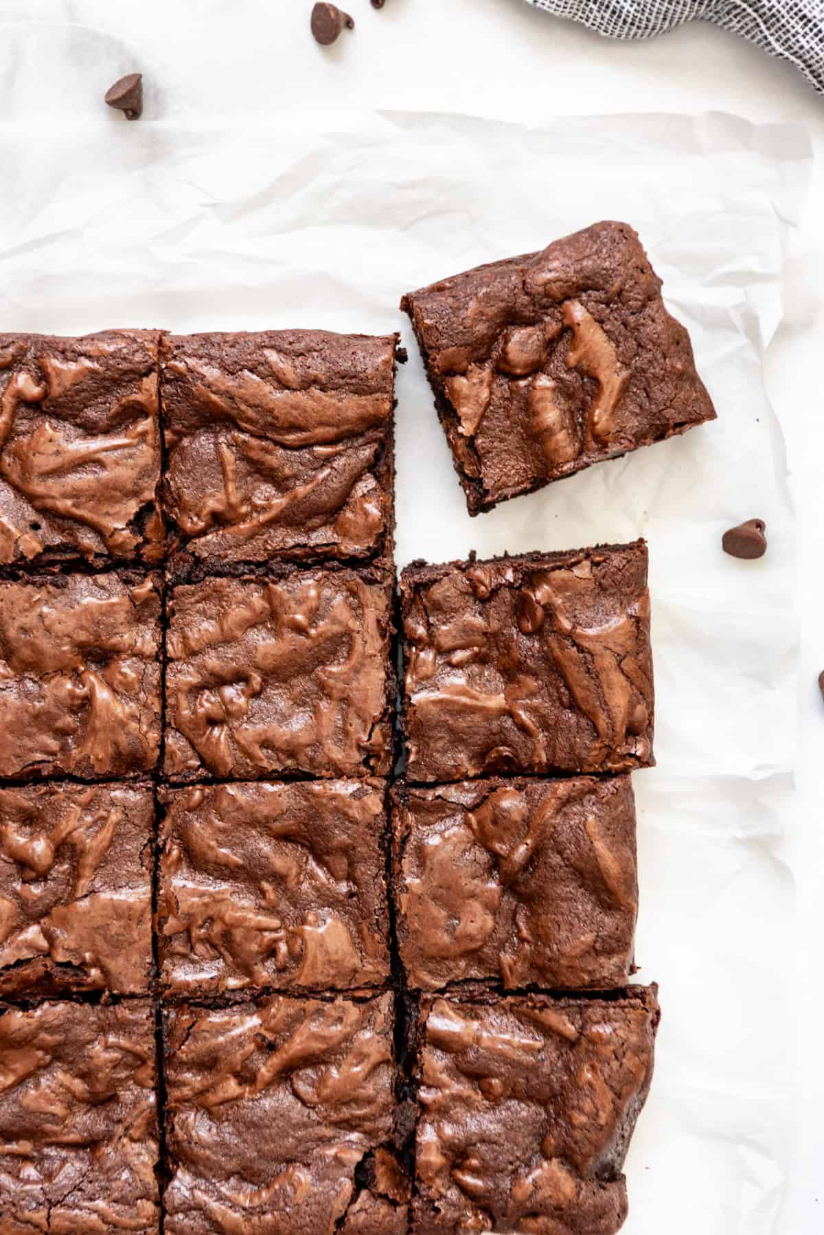 Brownies from scratch sliced into squares on a piece of parchment paper.