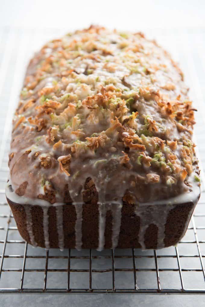 a side view of a loaf of coconut lime banana bread with drizzled glaze