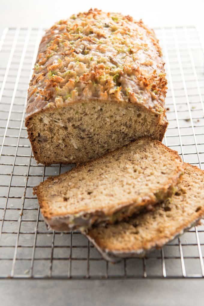 coconut lime banana bread with two slices removed resting on a wire rack