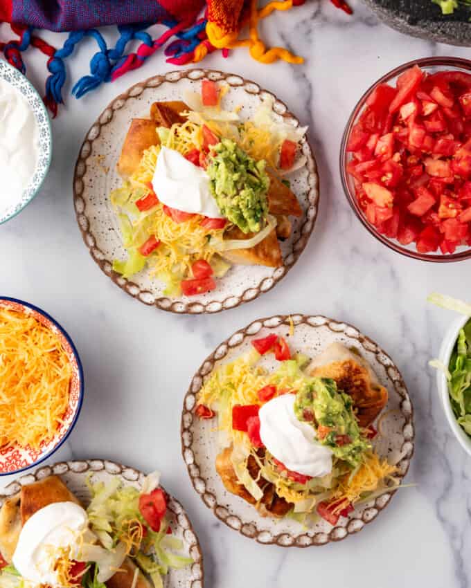 An overhead image of chimichangas on plates with lots of toppings.