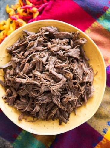 an aerial view of Slow Cooker Mexican Shredded beef in a yellow bowl